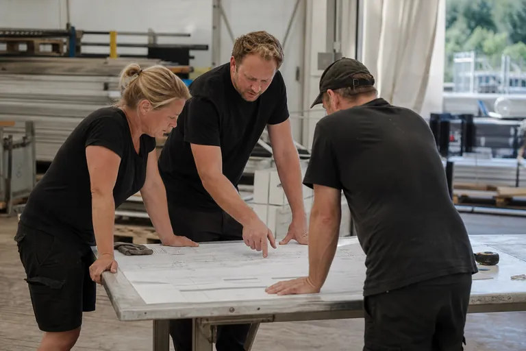 Projektleiterin, Monteur und Veranstalter stimmen sich anhand eines Lageplans ab.